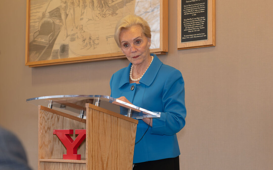 Dr. Helen Lafferty standing at a podium wearing a blue blazer, speaking at a bestowal ceremony.